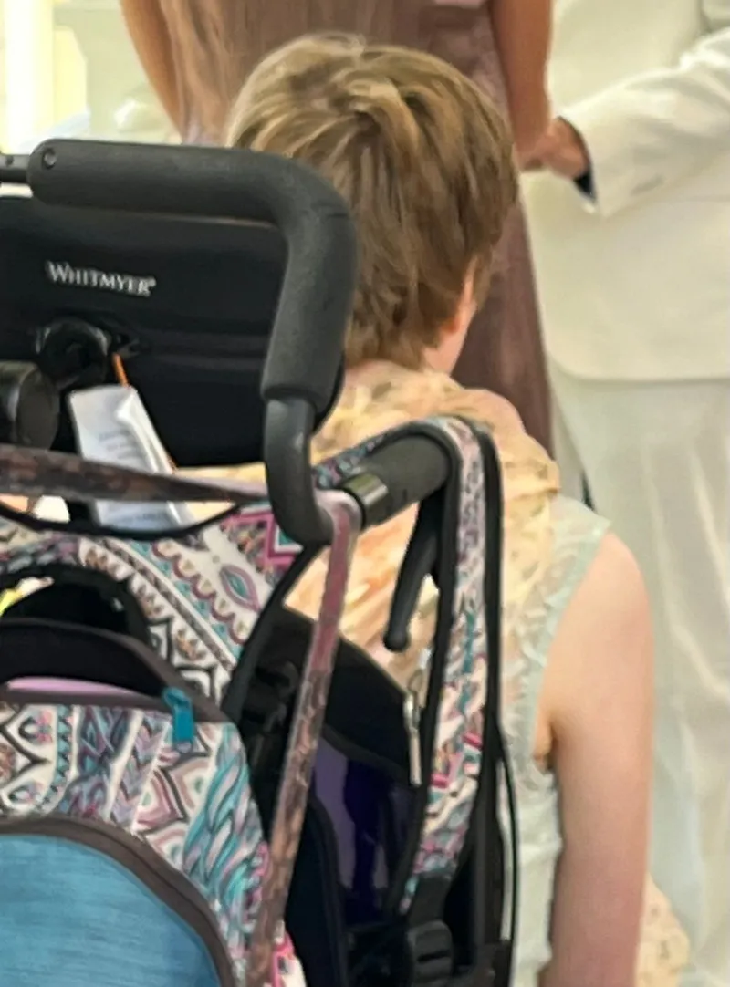 A young woman sitting in a wheelchair facing away from the camera